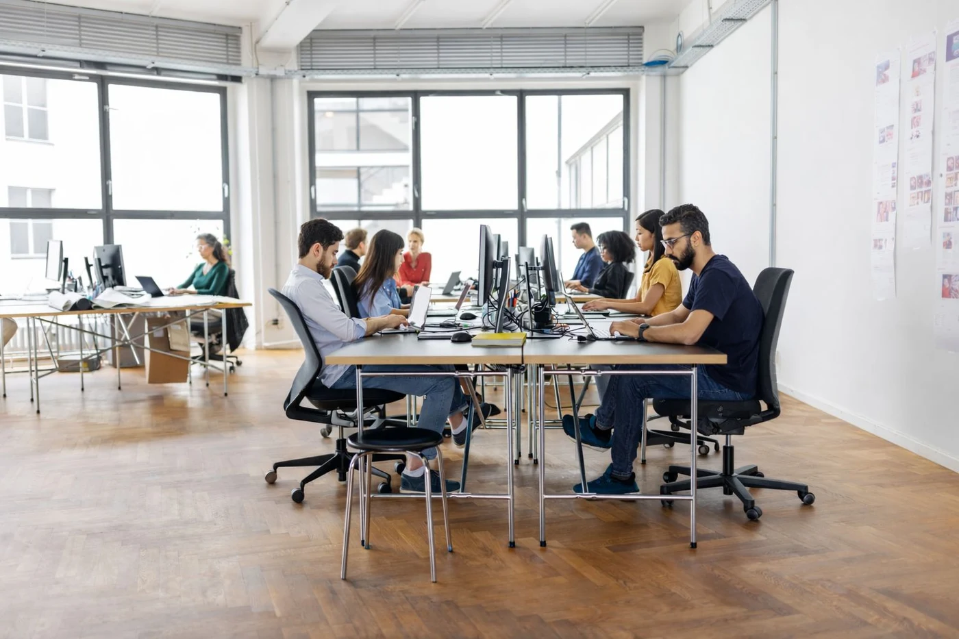 Product team working side by side at a shared desk in a bright open office