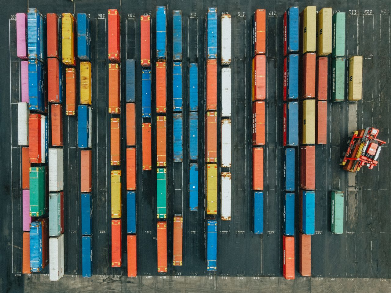 Vue aérienne de conteneurs alignés dans un centre logistique.